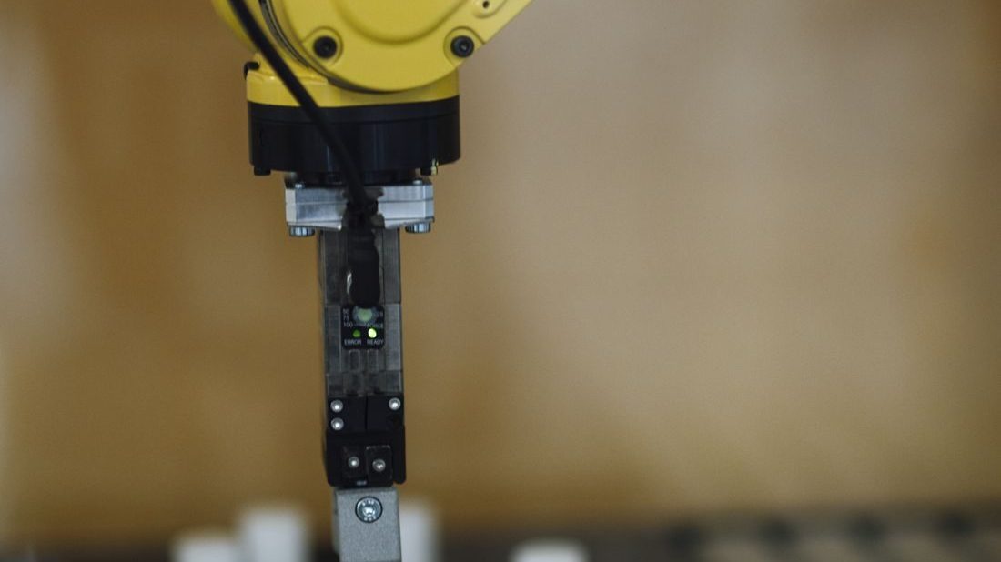 A yellow robotic arm in a lab, representing autonomous AI agents
